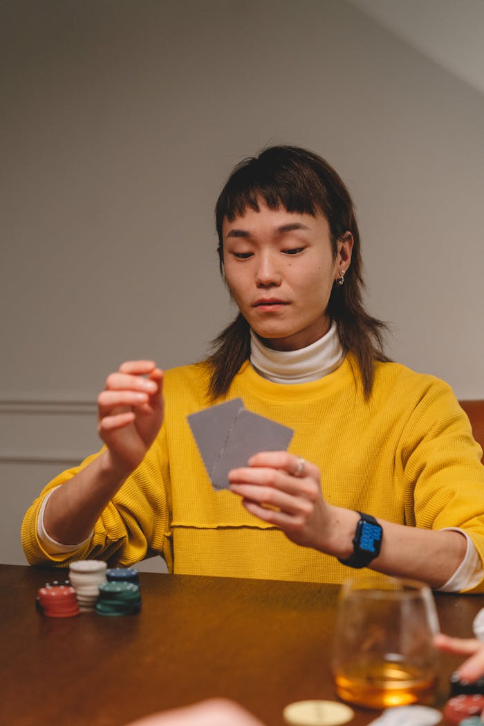Young woman focused while playing a card game at a table, indoors.